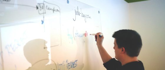 一位中型企业的市场负责人站在会议室白板前，手指着从怦怦整理出的行业动态摘要，向团队成员讲解竞品分析思路，背景是城市高楼窗景